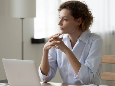 Woman thinking and looking away from her laptop 